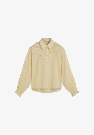 Blusa amarilla con cuello tipo camisa, botón en la parte delantera y detalle fruncido en el pecho. Mangas largas con puños elásticos y un corte holgado.