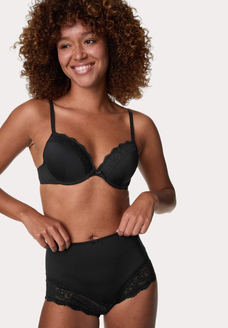 Reggiseno nero con bordi in pizzo e spalline regolabili, abbinato a slip neri a vita alta con simili dettagli in pizzo e una finitura liscia.