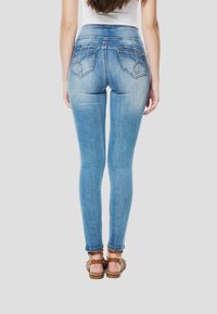 Blauwe skinny jeans van denim met een hoge tailleband, gebogen achterzakken met stiksel en een getailleerd silhouet tot aan de enkels.