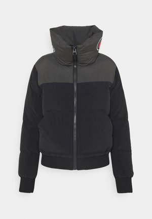 Giacca a vento nera con colletto alto, chiusura con zip frontale e polsini a coste. Presenta una striscia grigia sul petto e un dettaglio con logo sul colletto.