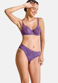 Paarse kanten beha en bijpassende slipset. De beha heeft ondersteuning met beugels, verstelbare schouderbanden en florale kantdetails. Gladde stofafwerking.