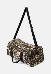 Bolso de viaje con estampado de leopardo, hecho de tela, con dos asas negras y una correa de hombro ajustable; extremos redondeados y cierre de cremallera.