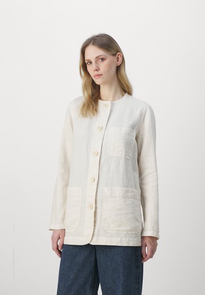 Veste en mélange de lin de couleur beige clair avec un col rond, fermeture à boutons à l'avant et deux grandes poches avant. Présente une surface légèrement texturée.