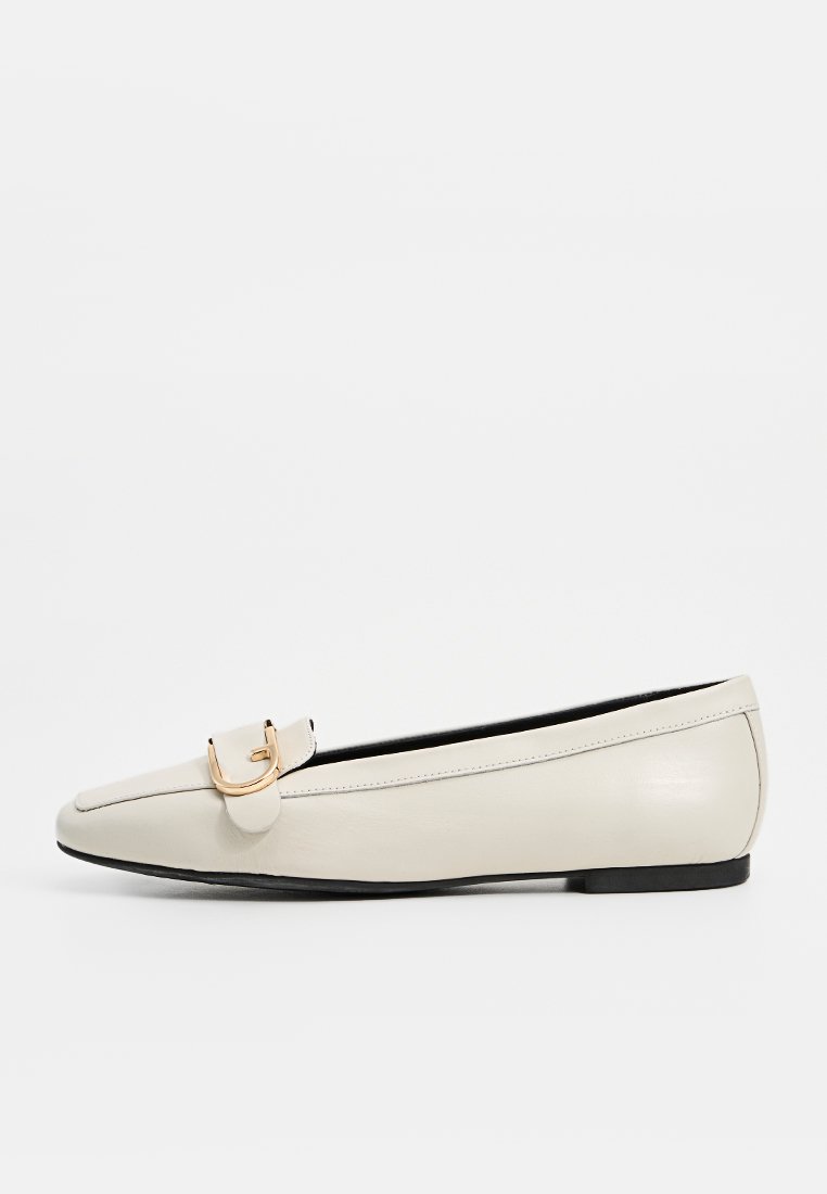 Leder-Ballerinas in Off-White mit spitzer Zehenform, ausgestattet mit einer Goldton-Schnallenakzentuierung und einer flachen schwarzen Gummisohle. Glatte Textur.