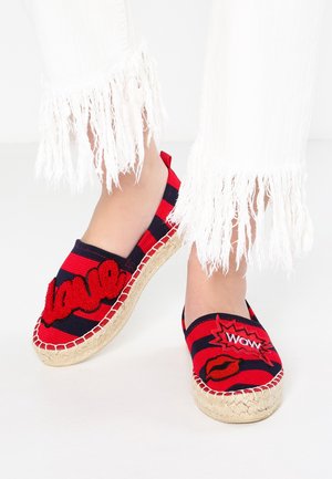 Czerwone i granatowe espadryle w paski z haftowanymi napisami "love" i "WOW", z juty podeszwą oraz frędzlami od białych spodni.