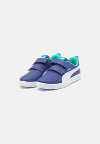 Baskets Puma avec un dessus synthétique bleu foncé, accents blancs, languette rembourrée et double strap Velcro. Semelle en caoutchouc blanc épais.