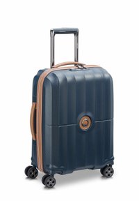 Valigia rigida blu con superficie testurizzata, dettagli beige, manico telescopico e quattro ruote girevoli per una facile manovrabilità.