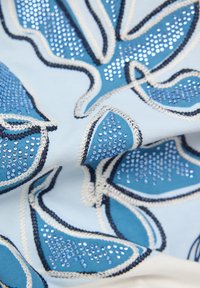 Blau bestickter Stoff mit Blattmustern, akzentuiert mit funkelnden Strasssteinen und kontrastierendem cremefarbenem und marineblauem Stich.