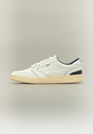 Baskets basses Vans blanches avec semelle beige, détails perforés sur les côtés et doublure foncée au talon et au col, vues de profil.