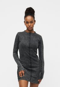 Φόρεμα με μακριά μανίκια σε σκουρό γκρι χρώμα, με ριμπ ύφανση και βολάν κατά μήκος των ακρών. Στενή εφαρμογή με στρογγυλή λαιμόκοψη.