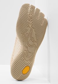 Femtåig beige skosula med texturerade mönster och gummi grepp. Har en orange Vibram®-logotyp vid hälen. Nätdesign för andningsförmåga.
