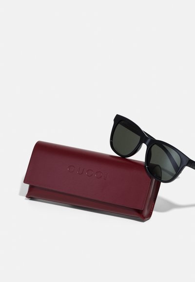 Gucci prillid mustade raamidega ja toonitud läätsedega, koos burgundia nahast kotiga, millel on brändinimi sisse pressitud.