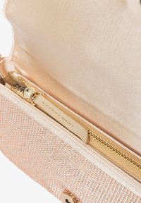 Borsa a mano di un morbido rosa con superficie texture e dettagli in metallo. Interno foderato in satin liscio; include un comparto con zip.