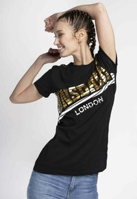 Black cotton t-shirt featuring bold gold and white text "LONSDALE LONDON" in a graphic design, short sleeves, and a relaxed fit.