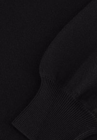 Maglione nero a maglia con polsini a coste, texture morbida e finitura liscia. Il design enfatizza la semplicità e uno stile monocromatico.