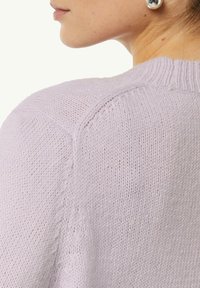 Helllila gestrickter Pullover mit ribbeligem Ausschnitt und strukturiertem Gewebe, das eine Nahaufnahme des Rückens und des Schulterbereichs zeigt.