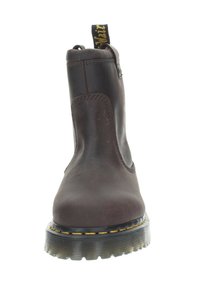 Stivali alla caviglia in pelle marrone con finitura liscia, lato elastico e un dettaglio di cucitura gialla lungo la suola. Presentano un cappio sul tallone per un'indossabilità facile.