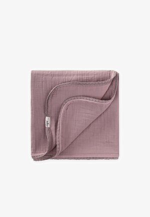 Couverture pour bébé mauve douce pliée avec des bords festonnés et une petite étiquette en tissu blanc sur un coin, sur fond blanc.
