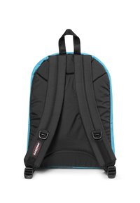 Zaino nero con bordini blu, dotato di spallacci imbottiti, maniglia superiore e fibbie regolabili. Tessuto liscio con una forma strutturata.
