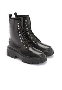 Svarta läderkampskor med en kraftig sula, med silverfärgade öglor, svarta snörningar och dragöglor högst upp för enklare påtagning.