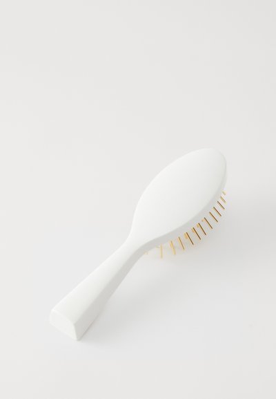 Άσπρη βούρτσα μαλλιών με λεία, στρογγυλεμένη λαβή και υφασμένη επιφάνεια. Διαθέτει χρυσές μεταλλικές τρίχες που είναι τοποθετημένες σε κυκλικό μοτίβο.