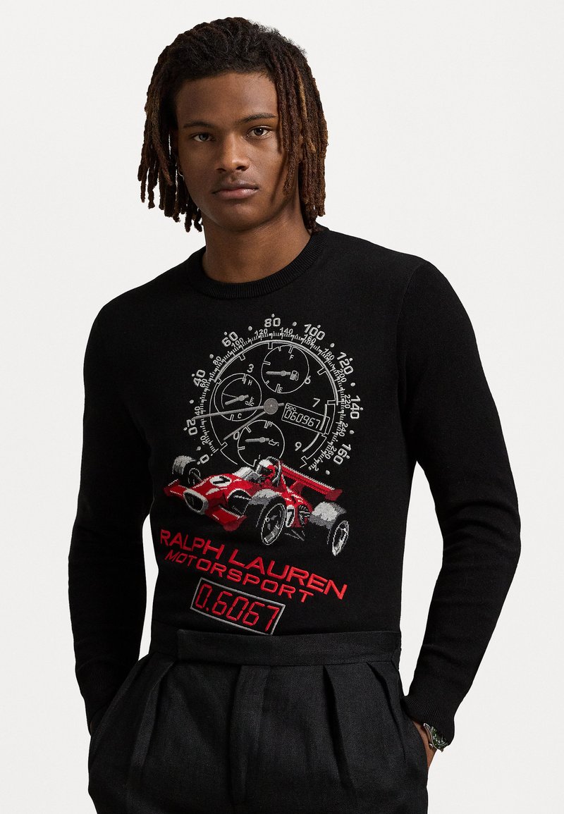 Pull en laine noire avec un graphique de voiture de course rouge et un compte-tours, portant le texte "RALPH LAUREN MOTORSPORT" en rouge. Coupe classique avec un col côtelé.