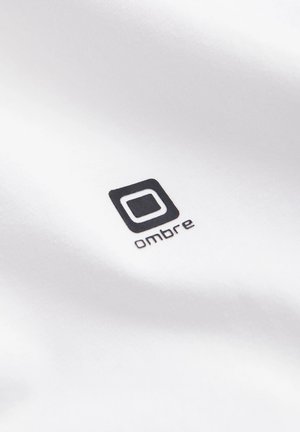 Bílá látka s černým logem se čtvercovým obrysem a slovem "ombre" napsaným malými písmeny. Hladká textura, minimalistický design.