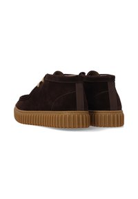 Braune Wildleder-Stiefel mit einer strukturierten Gummisohle, kontrastierenden Schnürsenkeln und zwei Zuglaschen an der Ferse für ein einfaches Anziehen.