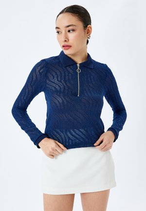 Granatowa polo z długim rękawem z zamkiem na szyi, posiadająca teksturowany, wzorzysty design siatki oraz kontrastowe, prążkowane mankiety.