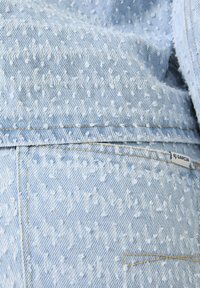 Lichtblauwe denimstof met een gestructureerde, gemêleerde weving. Bevat witte stiksels en een klein merkje met het label "GARCIA."
