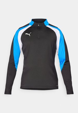 Cămașă sport neagră cu mâneci lungi, guler cu fermoar pe jumătate, panouri accent albastre și albe, și un mic logo alb pe piept. Textură de țesătură netedă.