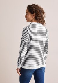 Randig sweatshirt i svart och vitt, med rund halsringning, långa ärmar och ribbade muddar. Mjuk textur med sidslitsar i fållen.