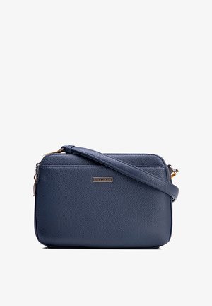 Křížová taška z texturované kůže v námořnicky modré barvě se zlatým zipem a nastavitelným popruhem, s malým kovovým logem značky vpředu.