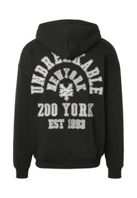 Sweat à capuche noir avec texte blanc disant "Unbreakable New York Zoo York Est 1993" et un logo stylisé au centre du dos.