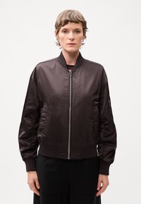 Brown bomber jacket made of smooth, shiny material with a front zipper, ribbed cuffs, and side pockets. Simplistic design with no visible patterns.