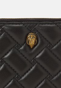 Portafoglio in pelle trapuntata nera con superficie texturizzata e hardware dorato, presenta un accento decorativo a forma di ghianda.