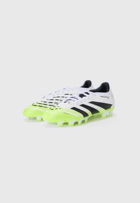 Soccer cleats featuring a white upper with black accents, vibrant green sole, textured design, and prominent three-stripe logo.