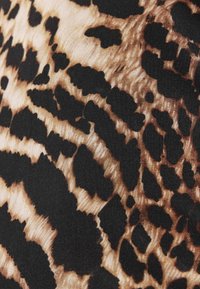 Lietussargu apdrukas audums ir melnbalts un bēšs dizains, ar neregulāriem leoparda līdzīgiem plankumiem un gludu, teksturētu virsmu.