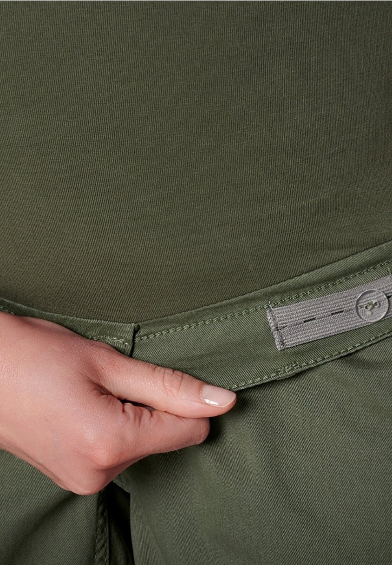 Tessuto in cotone misto verde oliva con un design rigato texture, dotato di passante per cintura e un'etichetta visibile vicino alla vita.