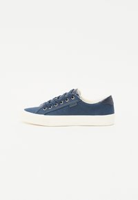 Marina canvas sneakers med guldöglor, vit gummisula och kontrasterande mörkblå hälslits. Klassisk snörningsdesign.