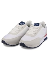 Weiße und beige Sneaker mit einer strukturierten Oberseite, Schnürsenkeln, navyfarbenen Akzenten und einer Gummisohle. Mit einem Logo auf der Zunge.