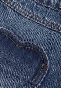 Denimtyg i mörkblått med en hjärtformad ficka med kontrasterande brun söm. Slät textur och jämn färg.