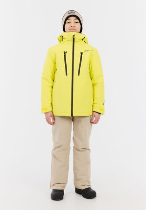 Felgeel waterdicht jack met een capuchon, zwarte ritsen en twee borstzakken. Draag dit met beige broek en zwarte laarzen.