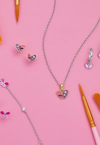 Collana in argento con pendente a farfalla in viola e rosa con due pietre trasparenti. Orecchini a forma di farfalla e bracciale esposti nelle vicinanze.