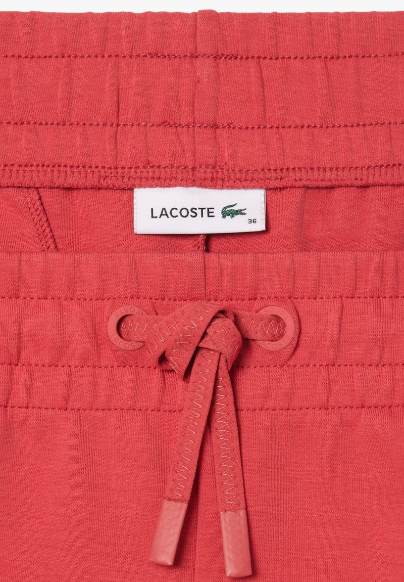 Rote Baumwollshorts mit einem elastischen Bund und Kordelzug, Lacoste-Logoschild und flach gestrickter Textur. Größe 36 angegeben.