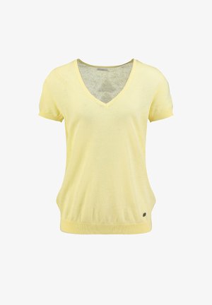 Hellgelbes Strickoberteil mit kurzen Ärmeln und V-Ausschnitt, mit gerippten Bündchen an Ärmeln und Saum, versehen mit einem kleinen runden Metall-Logo nahe dem unteren Saum.