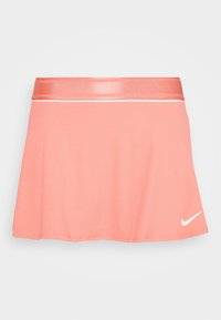 Falda deportiva rosa con textura acanalada, cinturilla brillante y detalle de una franja blanca. Presenta un pequeño logo blanco en el dobladillo.