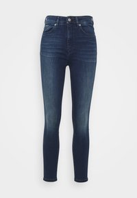 Jeans ajustados de mezclilla azul oscuro. Diseño de cintura alta con una textura suave, piernas ajustadas y detalles de desvanecimiento sutiles en los muslos y las rodillas.
