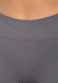 Szare legginsy w wysoki stan z żebrowanym pasem, wykonane z gładkiego, elastycznego materiału, podkreślające komfort i dopasowanie bez widocznych szwów.