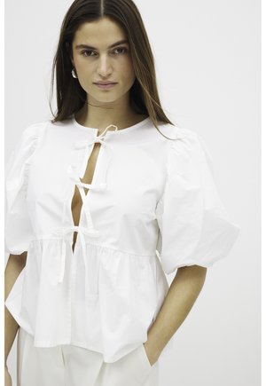 White cotton top with puff sleeves, a round neckline, and a tie closure at the chest. Features a flared hem and smooth texture.